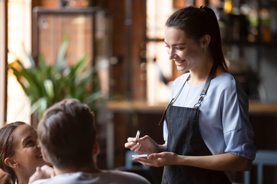 Smiling female waitress take order talk to clients couple